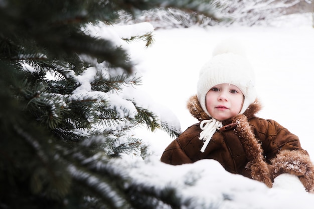 Small girl in a sled near fir-tree | Premium Photo