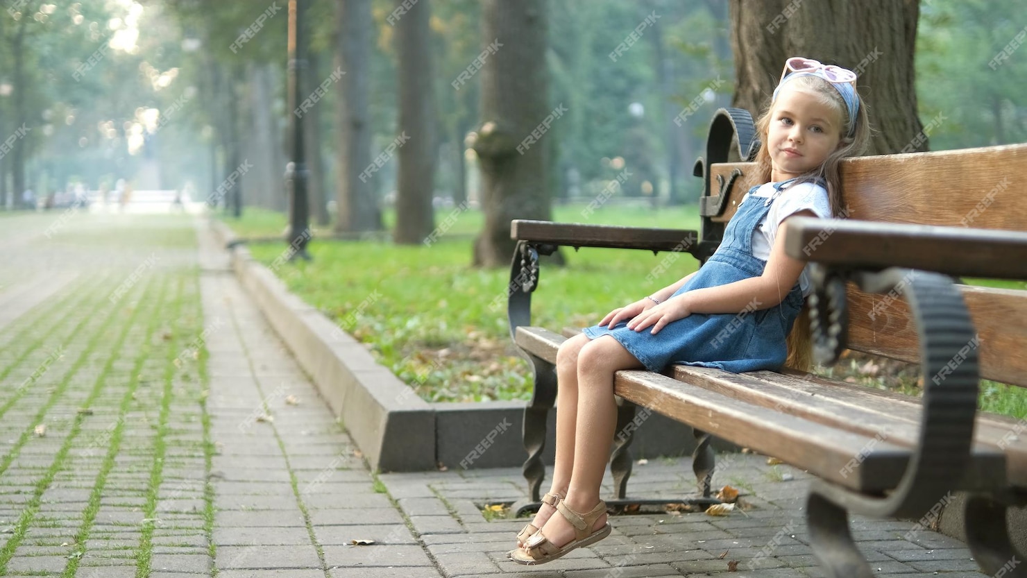 Premium Photo | Small happy child girl sitting on a bench resting in ...