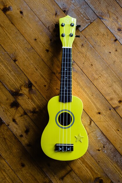 Premium Photo  Small yellow ukulele on wooden floor ready to be played