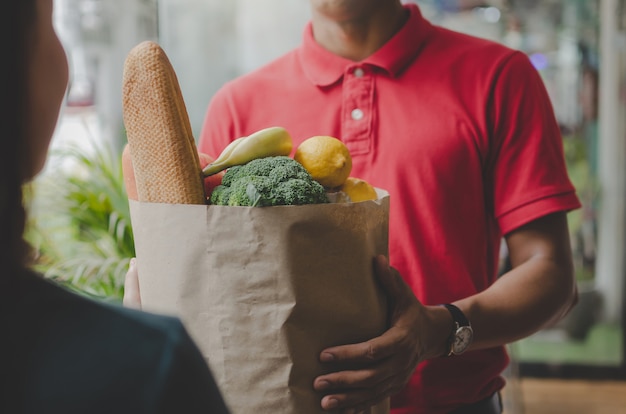 Smart food delivery service man in red uniform handing ...