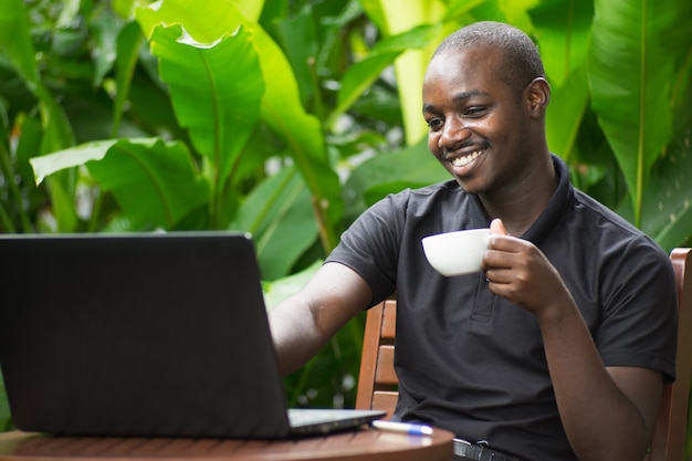 Premium Photo | Smile african man drink coffee with notebook in green