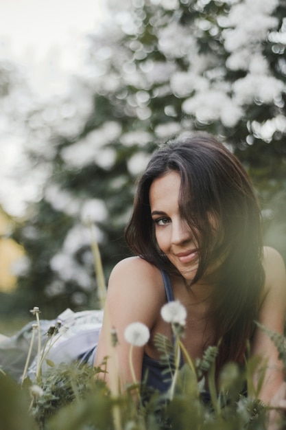 微笑んで魅力的な女性はまっすぐ見て緑の草の上に横たわる 無料の写真