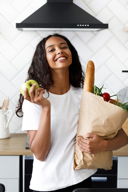 Smiled beautiful mulatto woman is holding package full ...