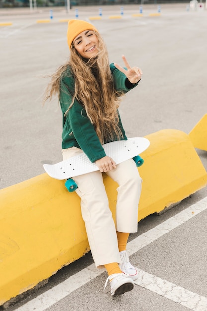 Free Photo | Smiley female with skateboard showing peace sign