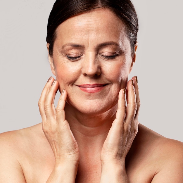 Free Photo Smiley Older Woman With Make Up On Posing With Hands On Face 