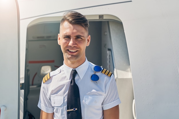 Premium Photo | Smiling airline male pilot standing in front of the ...