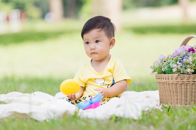 アジアの男の子の黒い髪と目の幼児を笑顔だけで緑の芝生に白い綿の上に座るとおもちゃを遊んで プレミアム写真