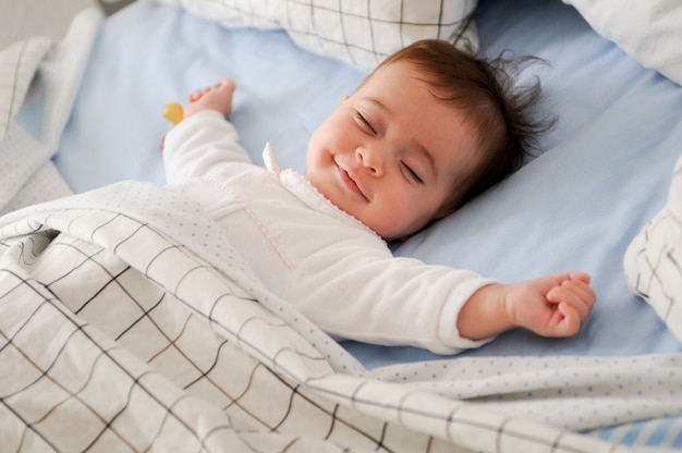 Smiling baby lying on a bed Free Photo