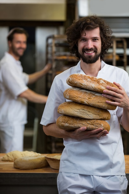 Free Photo | Smiling baker carrying stack of baked breads