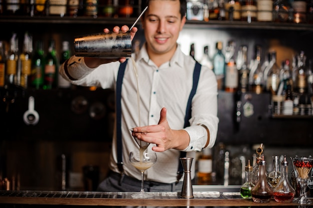 Premium Photo | Smiling bartender is making a coctail at the bar stand