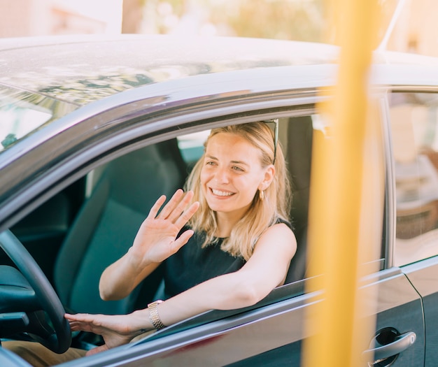 Free Photo Smiling Blonde Young Woman Driving The Car Waving He