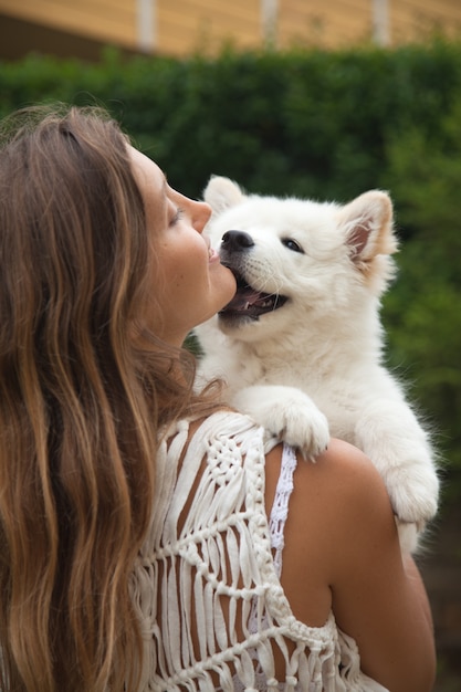 サモエドの子犬を両腕に抱えて笑顔の白人女性 ペットと人々のコンセプト かわいい動物のコンセプトです プレミアム写真