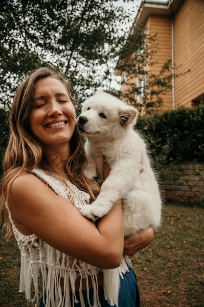 サモエドの子犬を両腕に抱えて笑顔の白人女性 ペットと人々のコンセプト かわいい動物のコンセプトです プレミアム写真