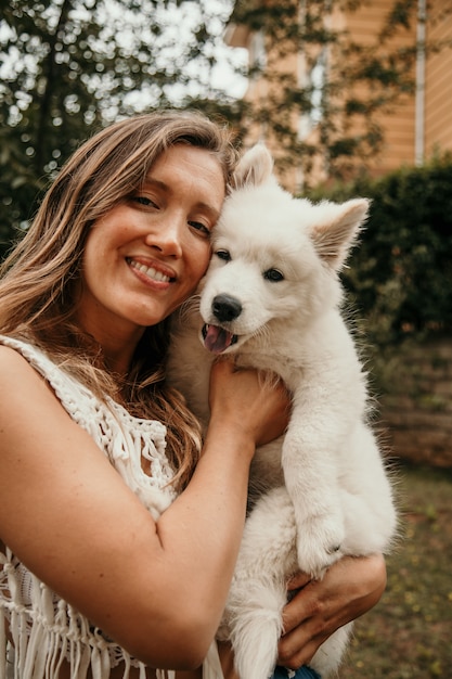 サモエドの子犬を両腕に抱えて笑顔の白人女性 ペットと人々のコンセプト かわいい動物 プレミアム写真