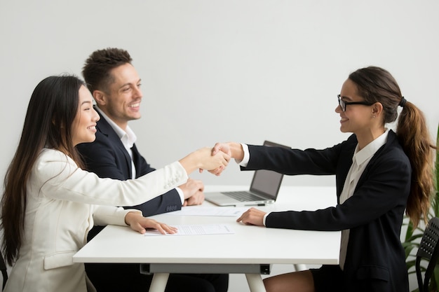 Smiling diverse businesswomen shake hands at group meeting, deal concept Free Photo