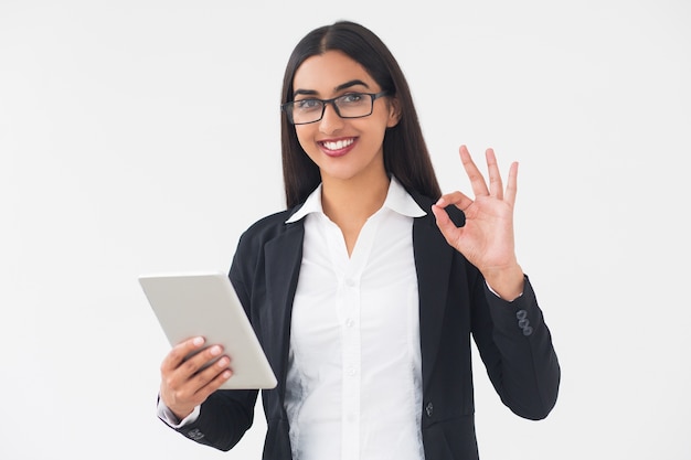 Smiling elegant woman with tablet showing ok sign Free Photo