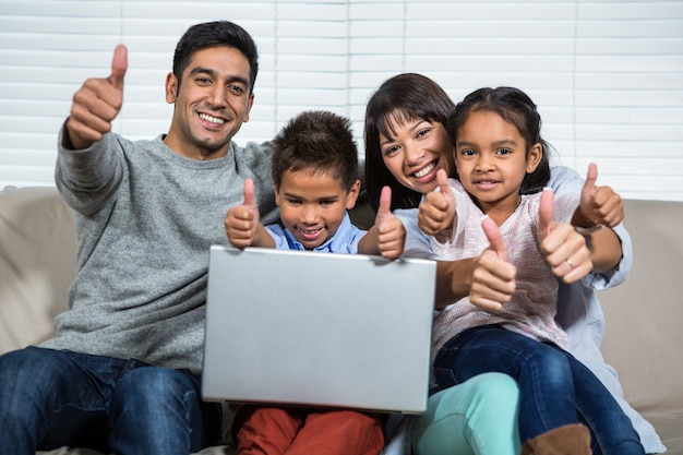 Smiling family on the sofa showing their thumbs up Premium Photo