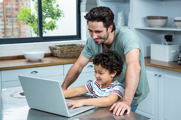 Premium Photo | Smiling father using laptop with his son