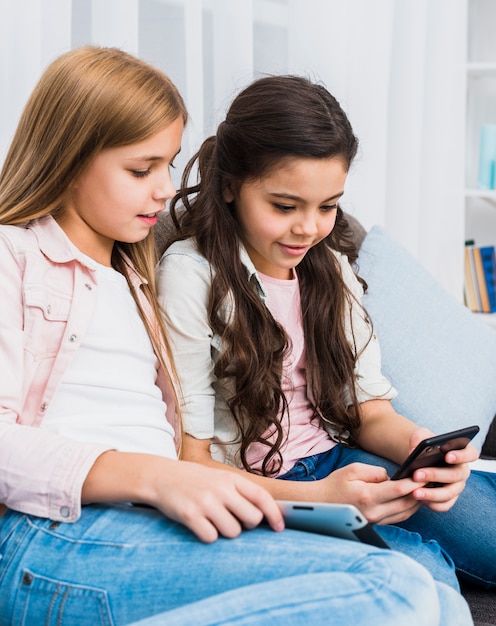 Free Photo | Smiling girl looking at her friend using mobile phone