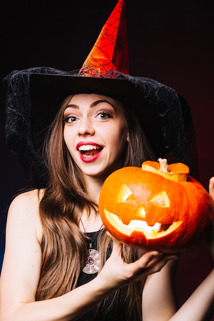 Free Photo | Smiling girl in witch hat with pumpkin