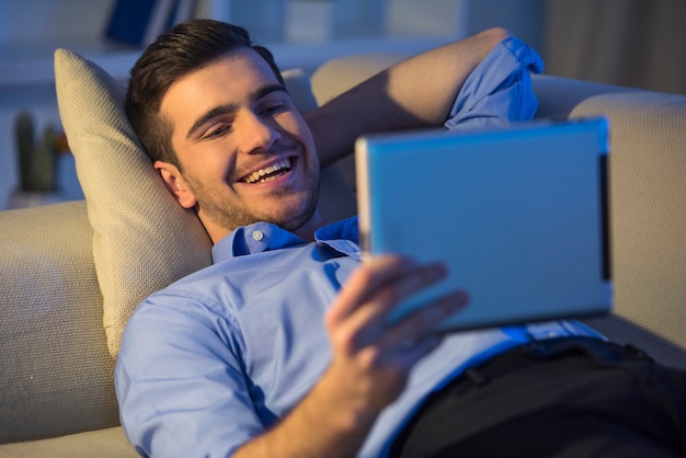 Smiling handsome man is using digital tablet at home. Premium Photo
