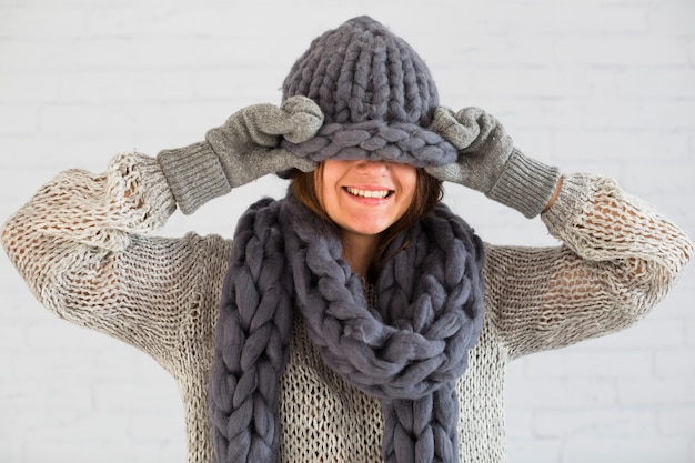 Smiling lady in mittens, scarf and hat on eyes  Free Photo