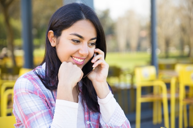 Smiling lovely woman talking on mobile phone in street cafe Free Photo
