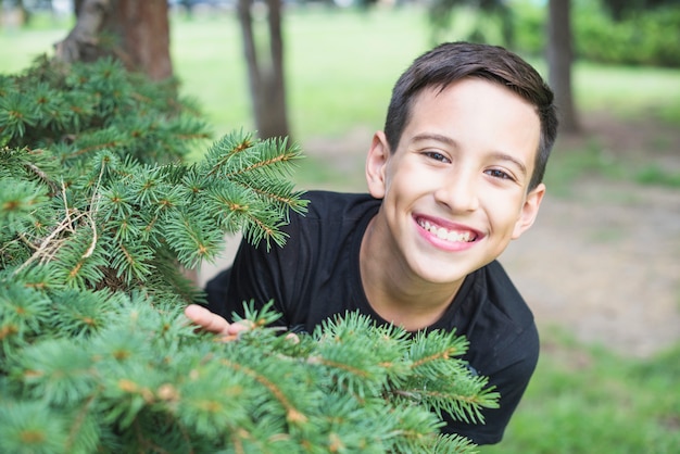 Smiling man standing near the green tree spruce branches Free Photo