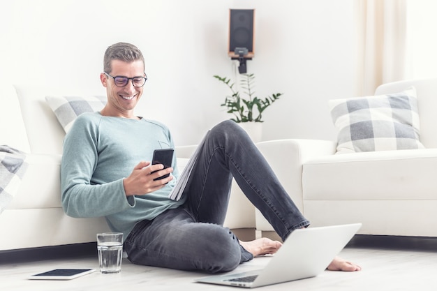 Premium Photo | Smiling man texts on his mobile phone during his home ...