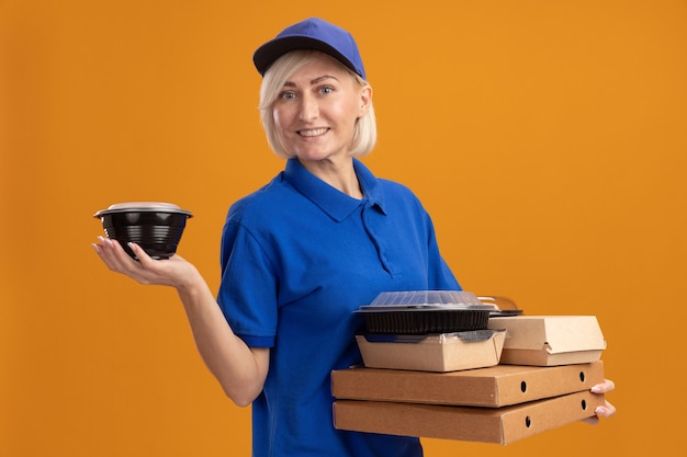 Free Photo Smiling Middle Aged Blonde Delivery Woman In Blue Uniform And Cap Holding Pizza