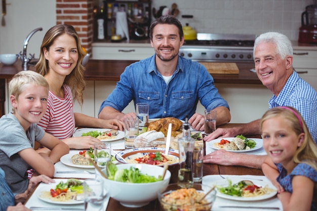 Premium Photo | Smiling multi generation family sitting at dining table