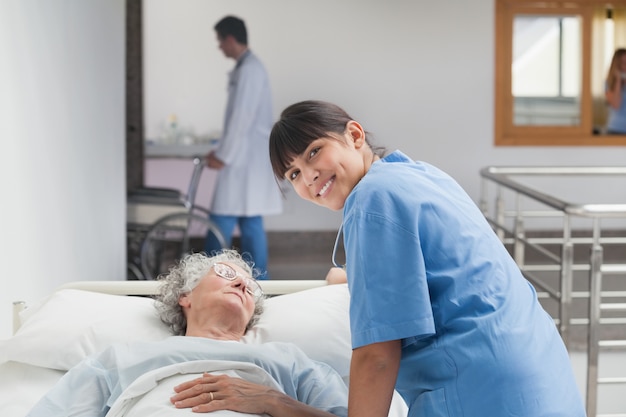 Premium Photo | Smiling nurse leaning on the bed of a patient