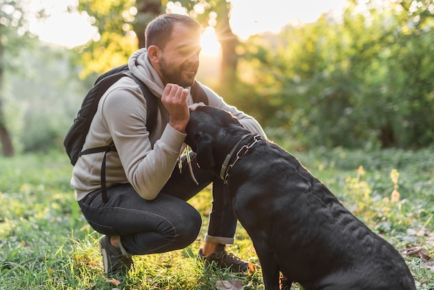 Free Photo | Smiling owner loving his black labrador in forest