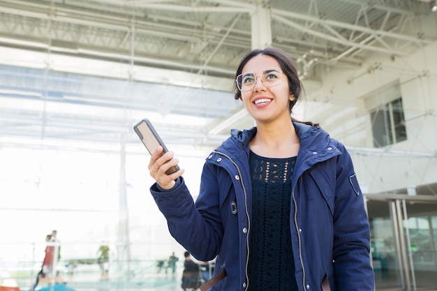 Smiling positive girl using phone outdoors Free Photo