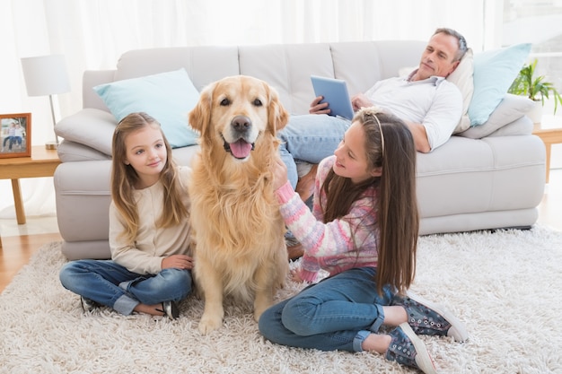 Premium Photo Smiling Sisters Petting Their Golden Retriever On Rug