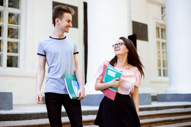 Smiling students going downstairs after clasees, having conversation, holding learning materials Premium Photo