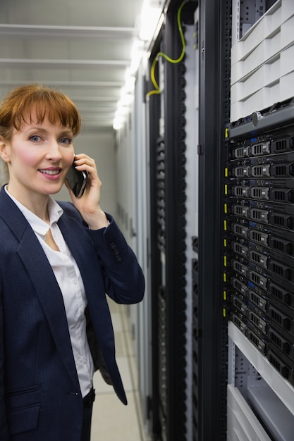 Smiling technician talking on phone while looking at server Premium Photo