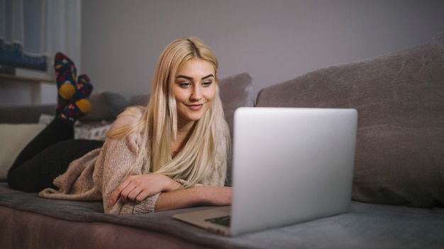 Free Photo Smiling Woman Browsing Laptop On Couch 