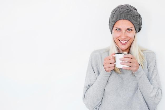 Smiling woman in hat holding hot drink Free Photo