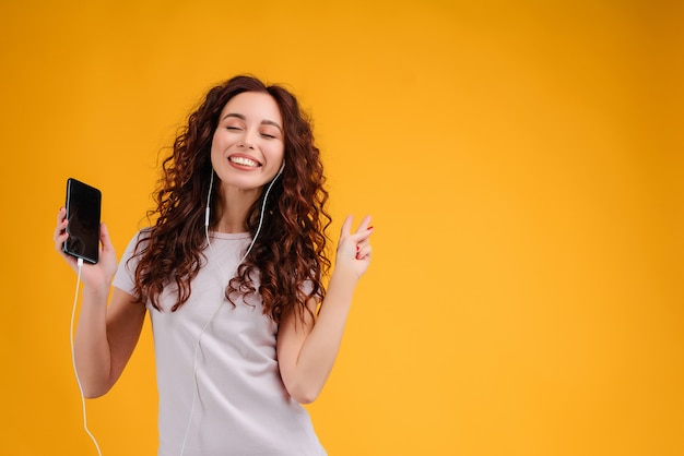 Premium Photo | Smiling woman listens to music from her phone and ear ...