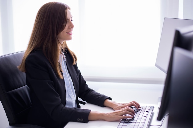 Free Photo | Smiling woman sitting typing on a computer