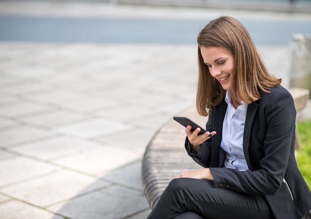 Smiling young business woman using her mobile cell phone Premium Photo