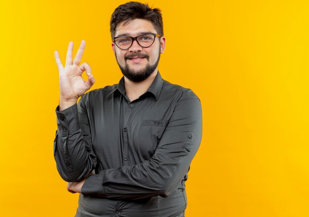 Free Photo Smiling Young Businessman Wearing Glasses Showing Okey Gesture Isolated On Yellow 0984