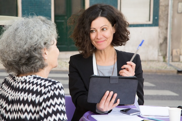 Smiling young consultant offering pen to elderly client Free Photo