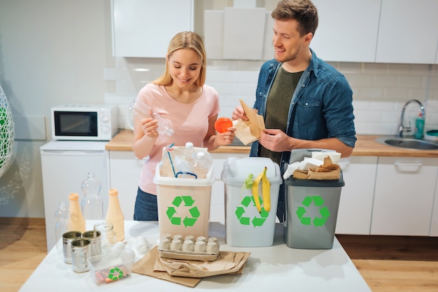 Premium Photo Smiling Young Couple Putting Plastic Paper And Other Waste In Garbage Bio Bins In The Kitchen