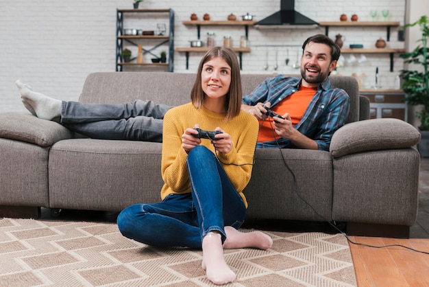 Smiling Young Couple Relaxing At Home Playing The Video Game At