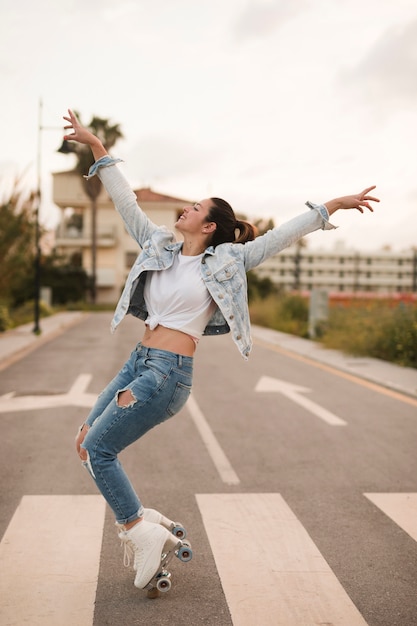 Free Photo | Smiling young female skater dancing with roller skate on road