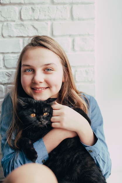 笑顔の若い女の子は黒猫を抱擁します プレミアム写真