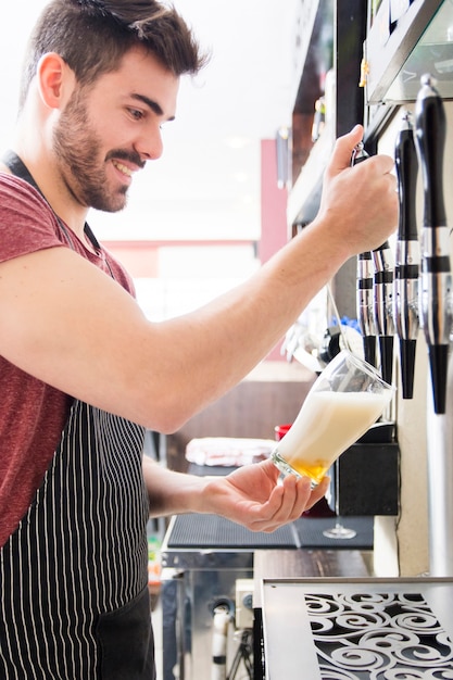 Free Photo Smiling young male bartender  pours fresh 
