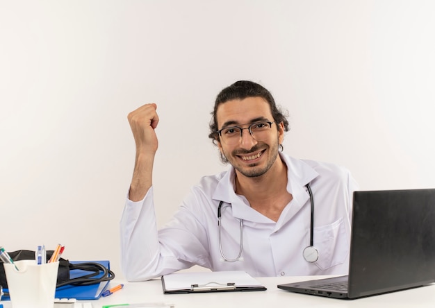 Smiling young male doctor with medical glasses wearing medical robe with stethoscope Free Photo